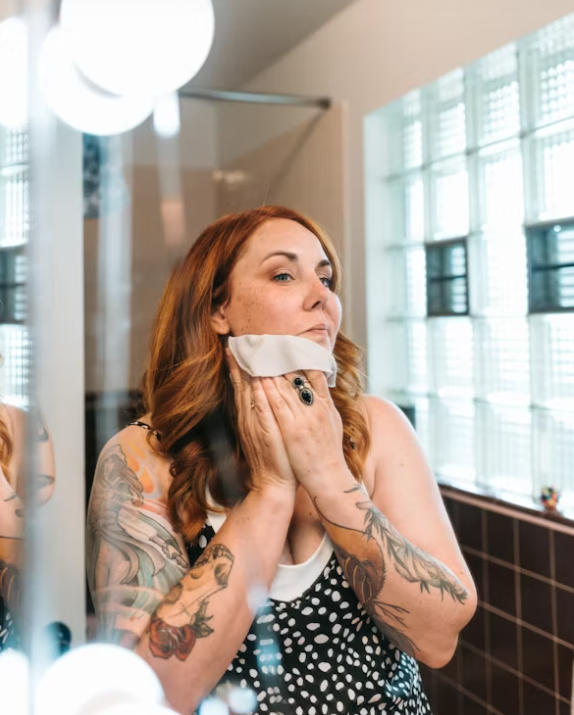 Applying a non-stripping cream cleanser to damp skin to remove makeup and soothe the skin barrier.